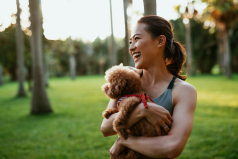 Woman carrying her dog happily in the park