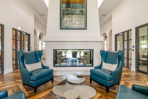 Community lobby with large leather armchairs, sculptural coffee table, and fireplace