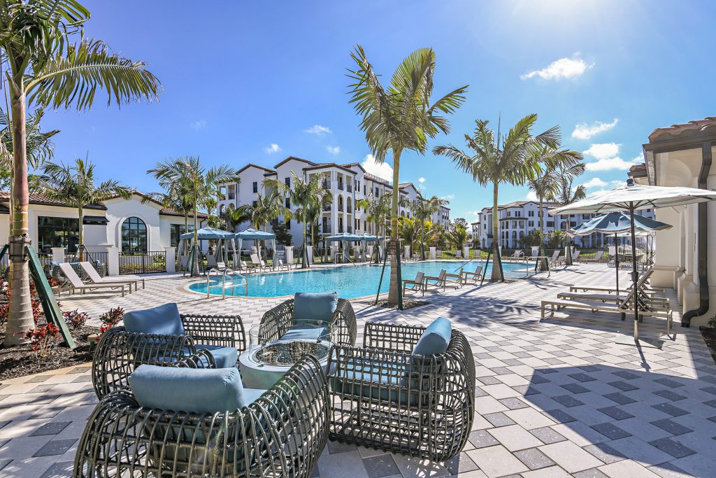 Swimming pool area with shaded seating, tropical landscaping, and water fountain