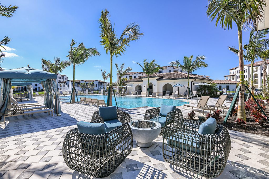 Swimming pool area with shaded seating, tropical landscaping, and water fountain
