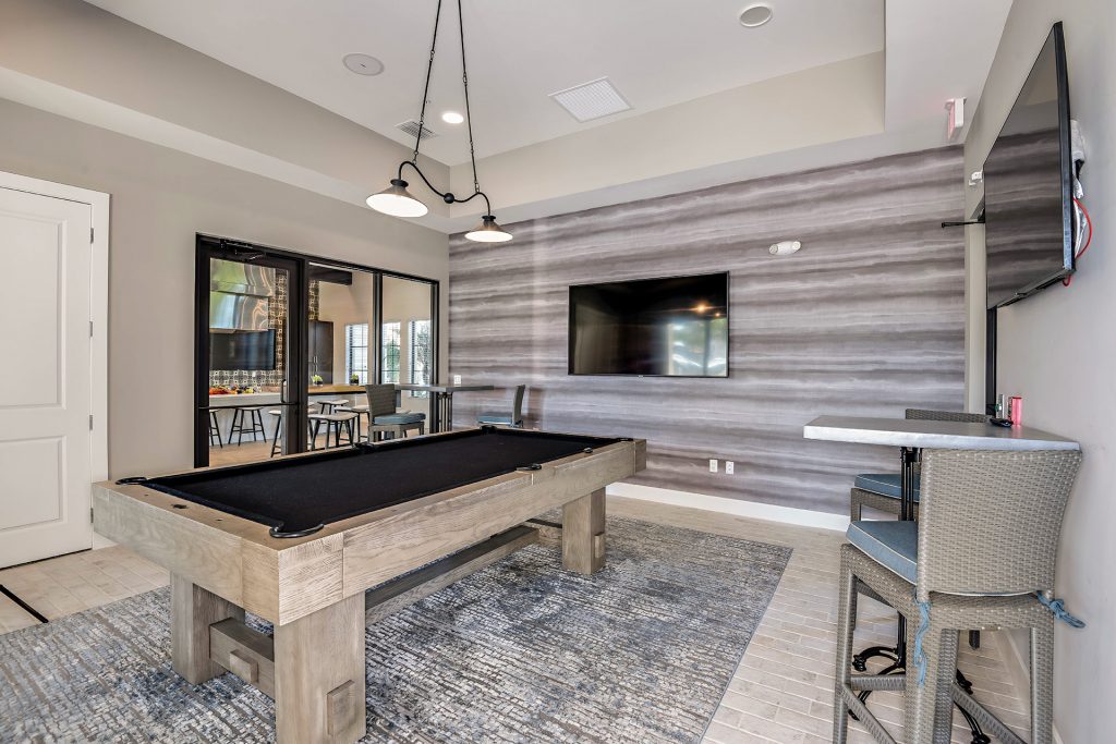 Indoor gaming area with pool table, seating, and televisions