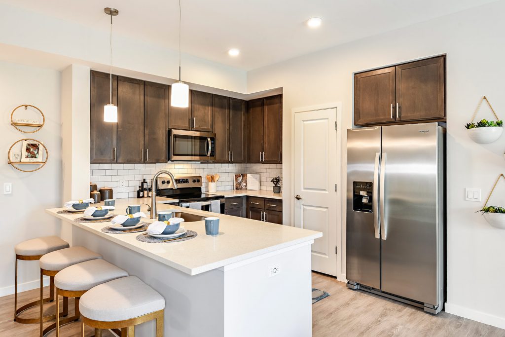 Kitchen area with island, single sink, steel appliances, wood cabinets, and seating