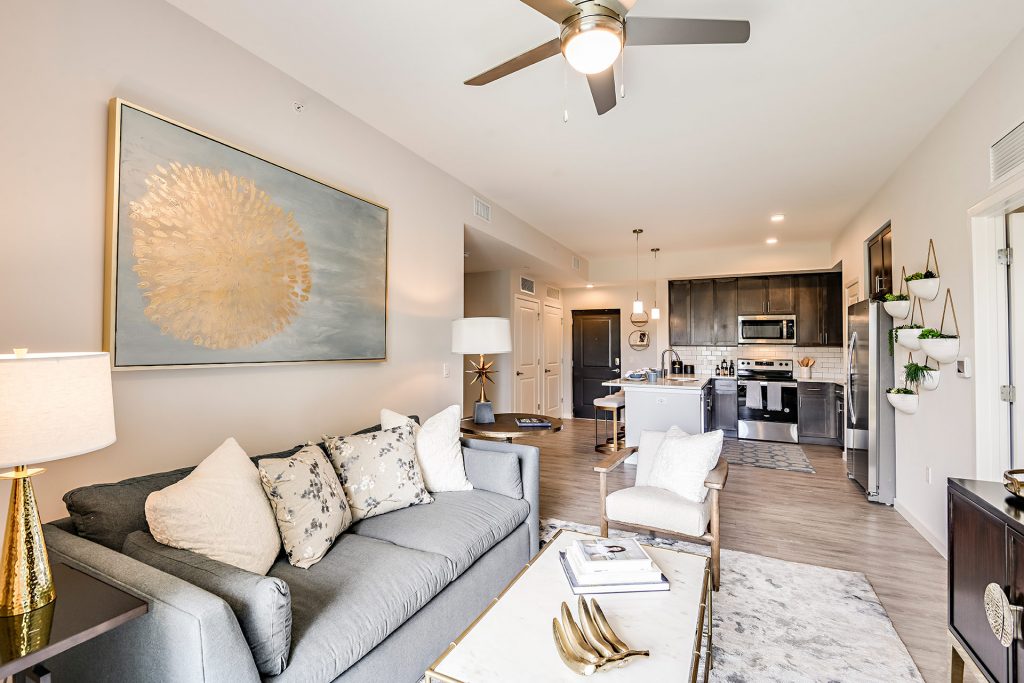 Living room with couches, lounge seating, wall paintings, and ceiling fans