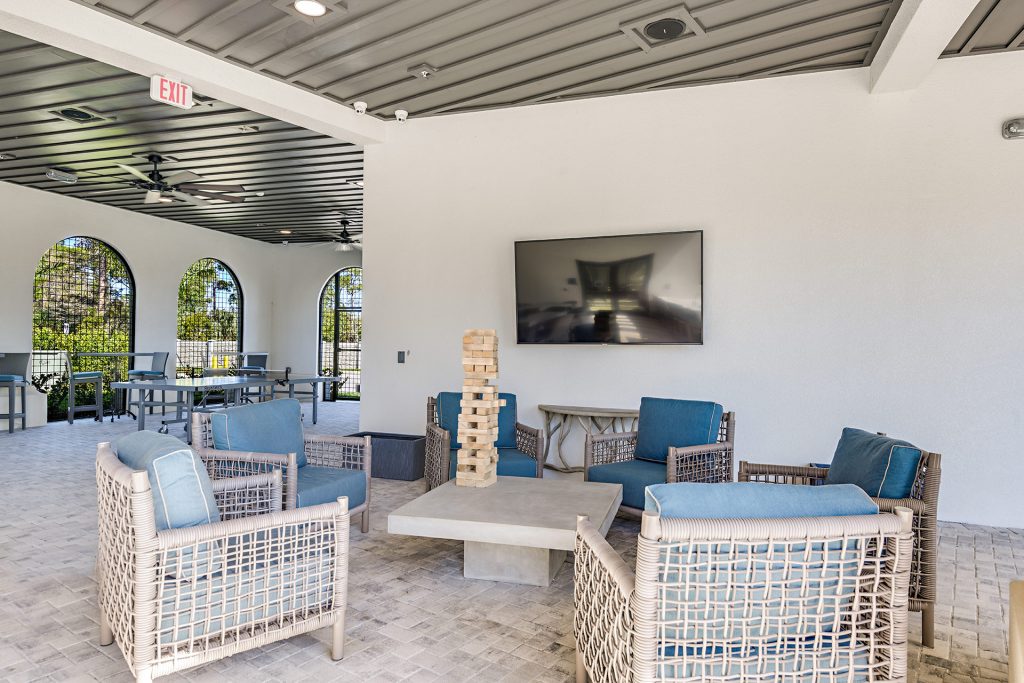 Outdoor covered seating area with jenga blocks, ceiling fans, and television