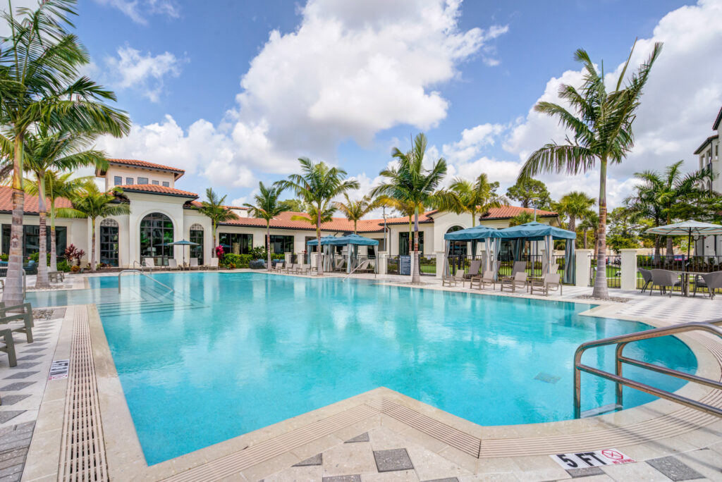 Swimming pool area with shaded seating and sun tanning beds and tropical landscaping