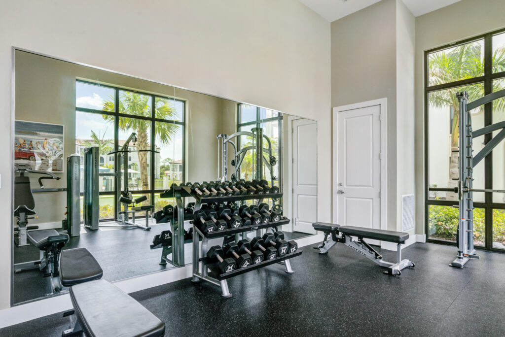 Indoor gym area with floor to ceiling windows, mirror, and hand weights