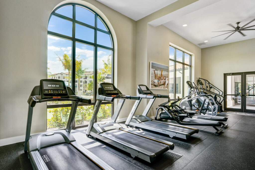 Indoor gym area with floor to ceiling windows, ceiling fan, and cardio machines