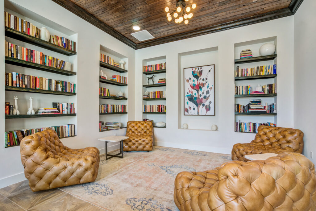 Indoor clubhouse with lounge chairs, book shelves, designer lighting, and decor
